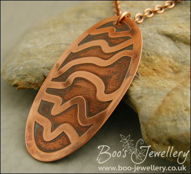 Oval copper pendant etched with random stripes
