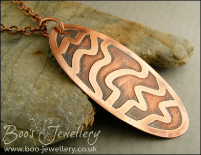 Oval copper pendant etched with random stripes