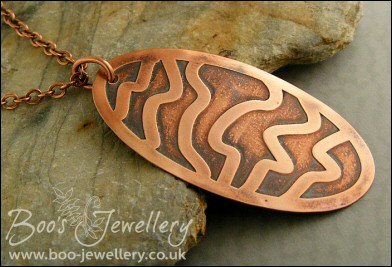 Oval copper pendant etched with random stripes