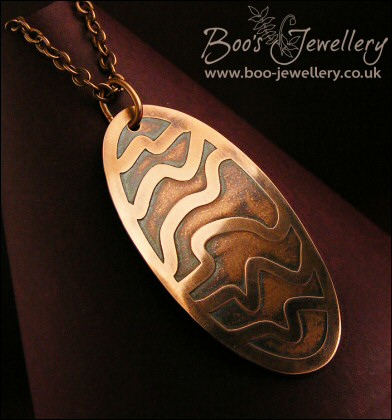 Oval copper pendant etched with random stripes