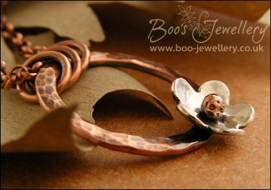 Hammered copper ring pendant with silver flower