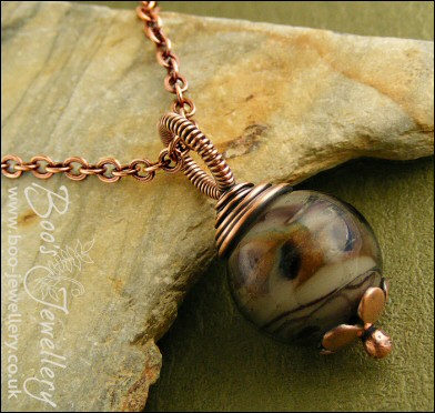 Dark glass and copper wire wrapped pendant on chain