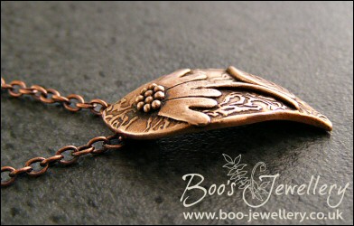Wave shaped curvy copper pendant with relief daisy design