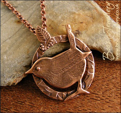 Circle shaped pendant featuring a hand sculpted wren