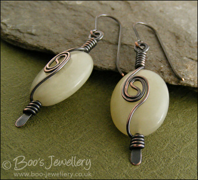 Pale green oval earrings with a dark copper spiral