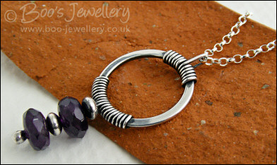 Silver circle pendant wrapped with faceted amethyst rondelles