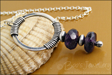 Silver circle pendant wrapped with faceted amethyst rondelles