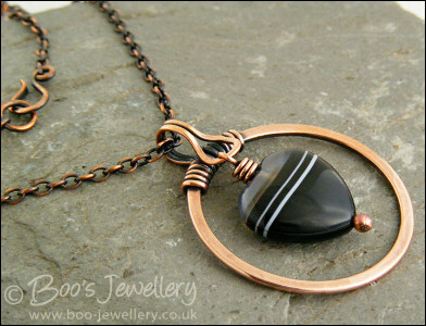 Antiqued copper circle pendant with banded black heart gemstone