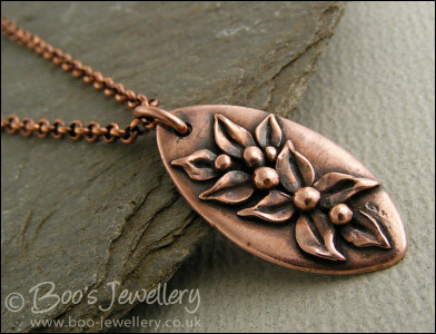 Antiqued copper oval pendant with hand sculpted leaves and buds