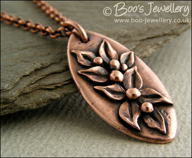 Antiqued copper oval pendant with hand sculpted leaves and buds