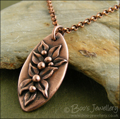 Antiqued copper oval pendant with hand sculpted leaves and buds