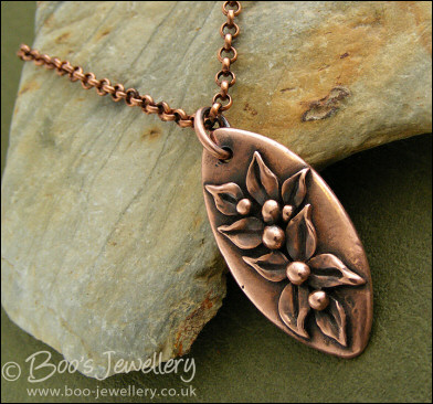 Antiqued copper oval pendant with hand sculpted leaves and buds