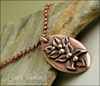 Antiqued copper oval pendant with hand sculpted leaves and buds