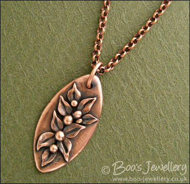 Antiqued copper oval pendant with hand sculpted leaves and buds