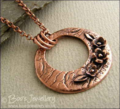 Circle pendant with hand sculpted flowers and leaves