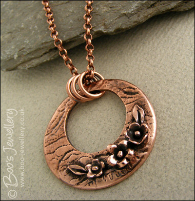 Circle pendant with hand sculpted flowers and leaves