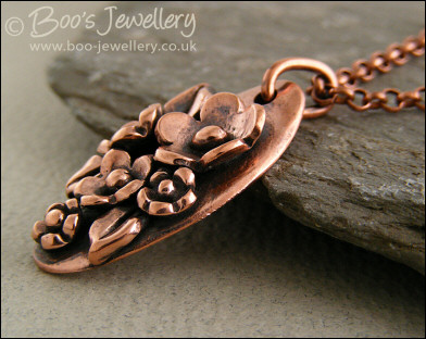 Hand sculpted oval pendant with flowers and leaves