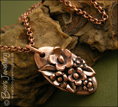 Hand sculpted oval pendant with flowers and leaves