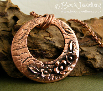 Circle pendant with hand sculpted flowers and leaves