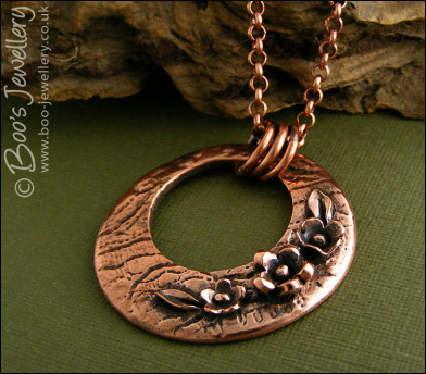 Circle pendant with hand sculpted flowers and leaves
