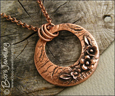 Circle pendant with hand sculpted flowers and leaves