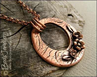Circle pendant with hand sculpted flowers and leaves